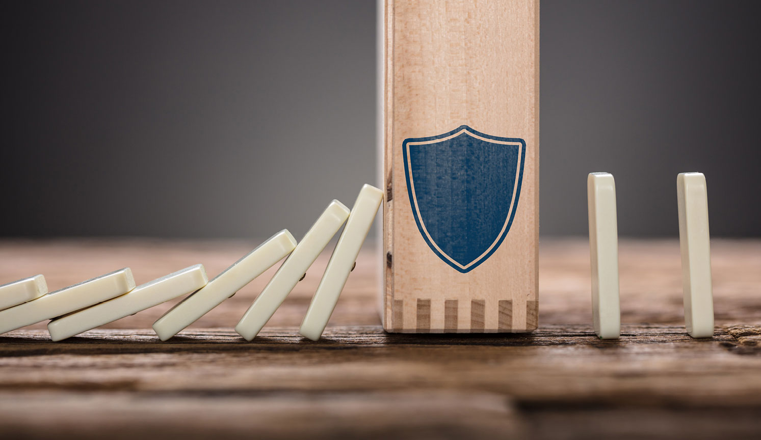 falling dominos being stopped by a wooden block with a navy shield on it